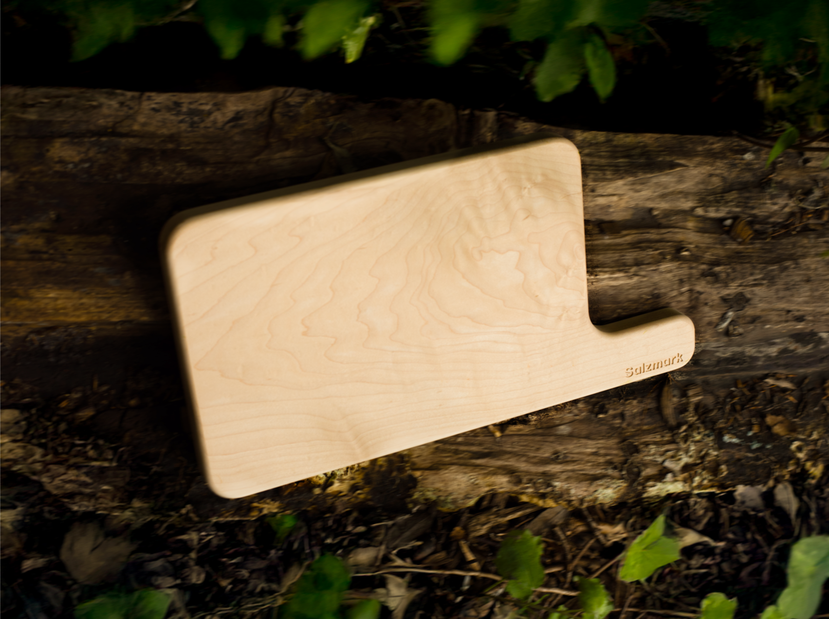 Wooden cutting board on a rustic wooden surface with greenery