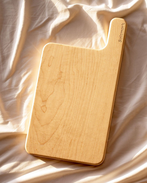 Wooden cutting board on a textured beige fabric surface