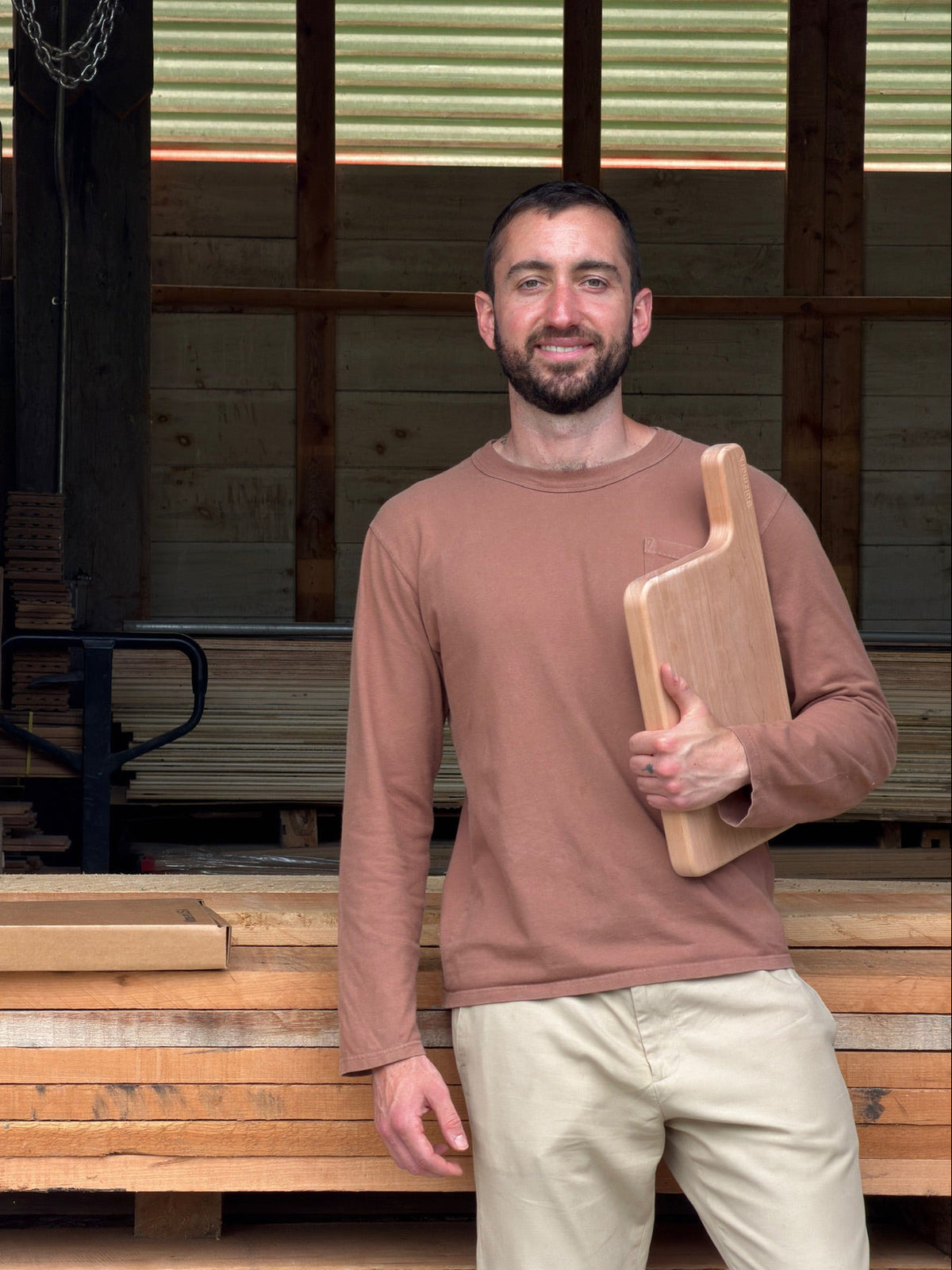 founder holding board in woodshop.