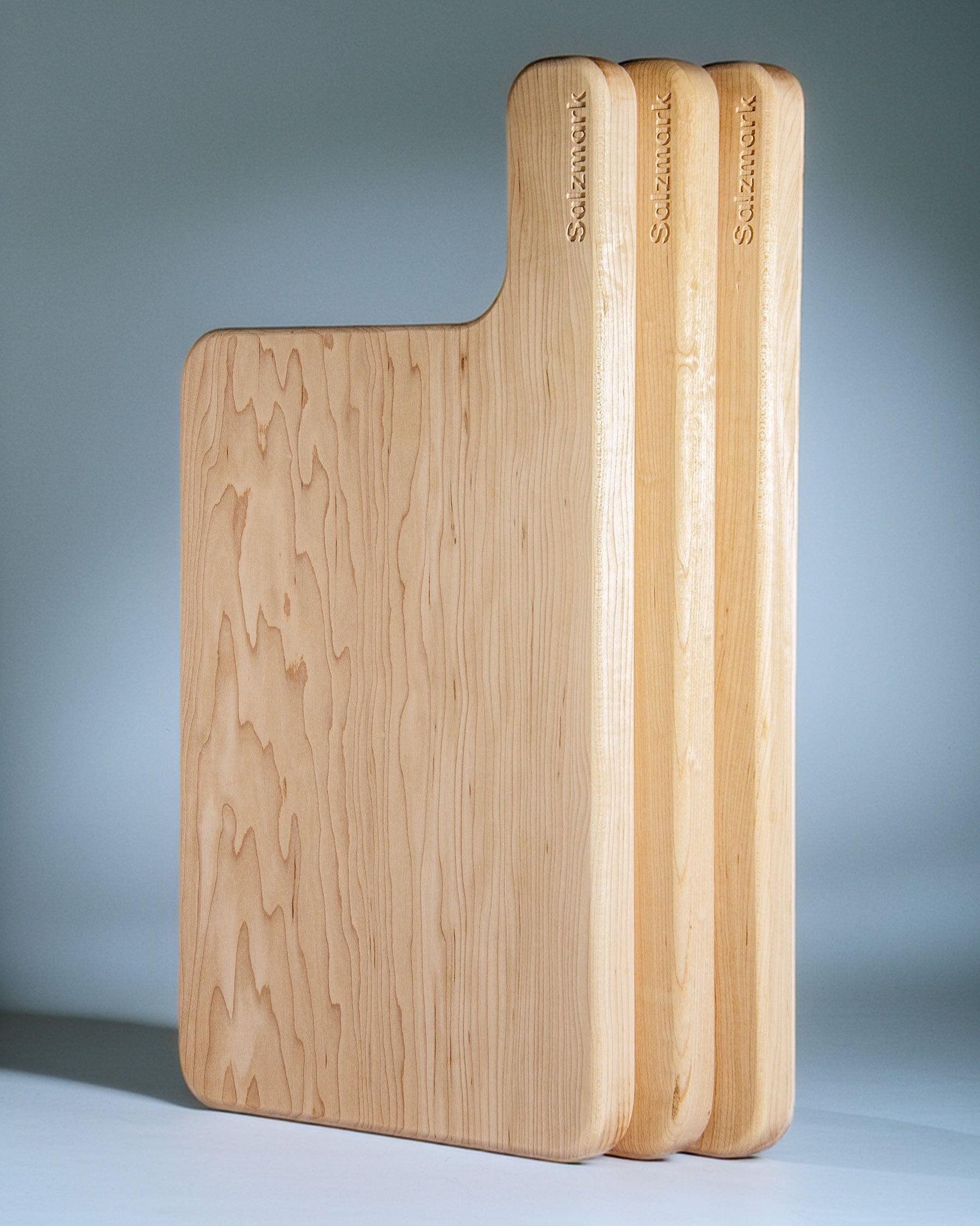 Set of wooden cutting boards with 'Salzmark' branding on a gray background

